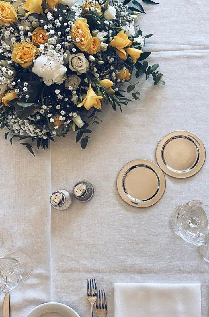 Centrotavola di rose bianche e fiori gialli su una tavola apparecchiata