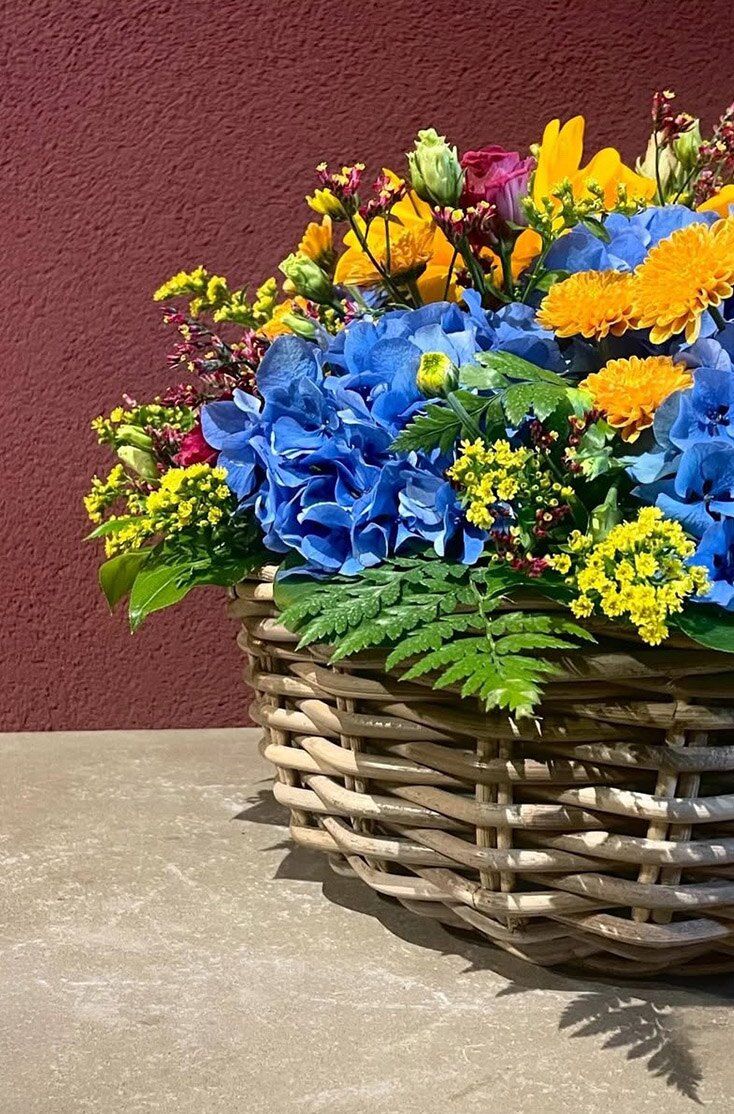 Cesto in vimini con ortensie blu, girasoli e felci