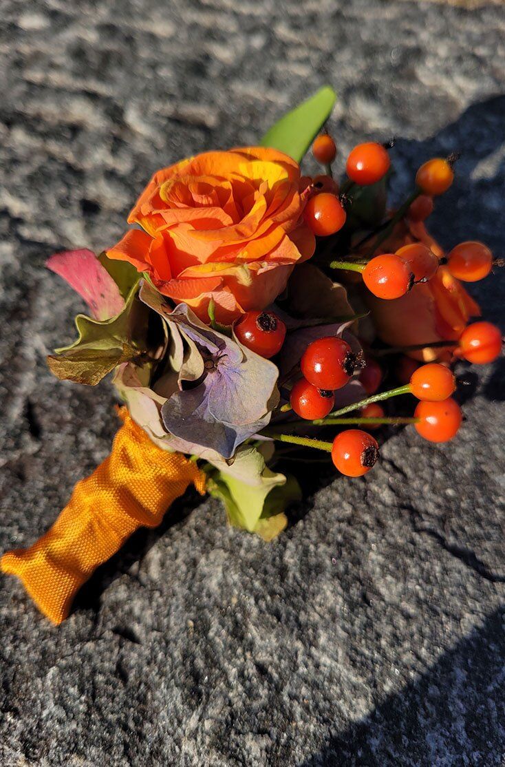 Piccolo bouquet di rose arancio e bacche su una pietra