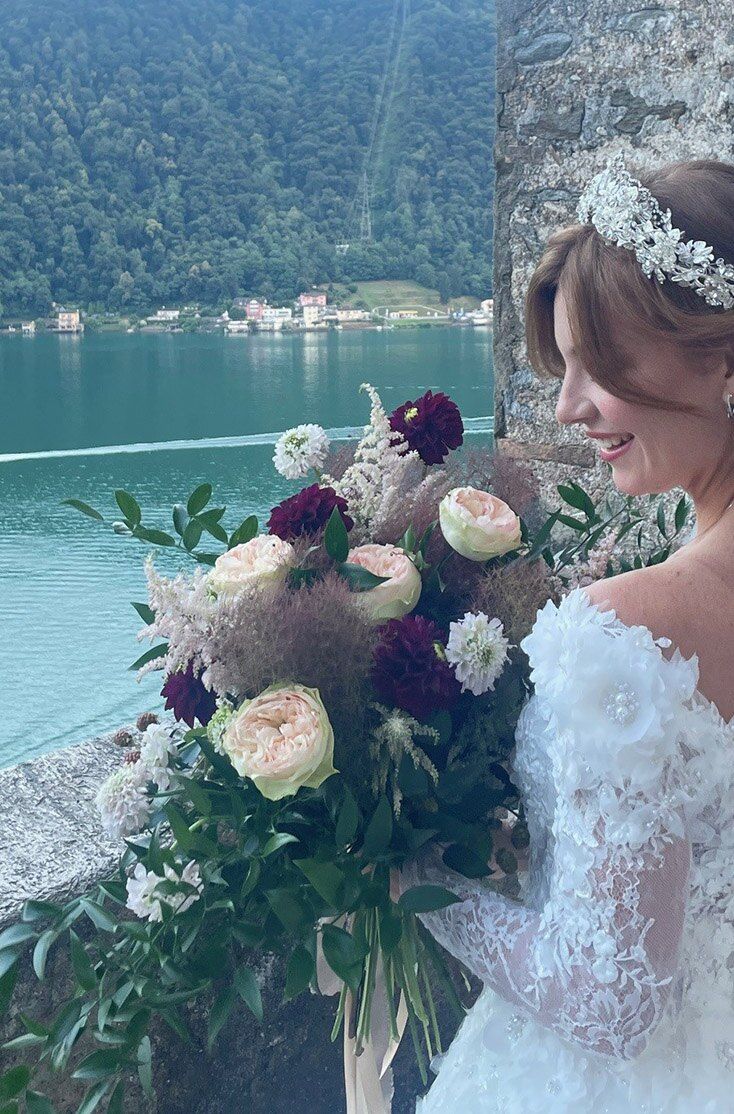 Sposa con un bouquet di fiori viola e bianchi in riva al lago