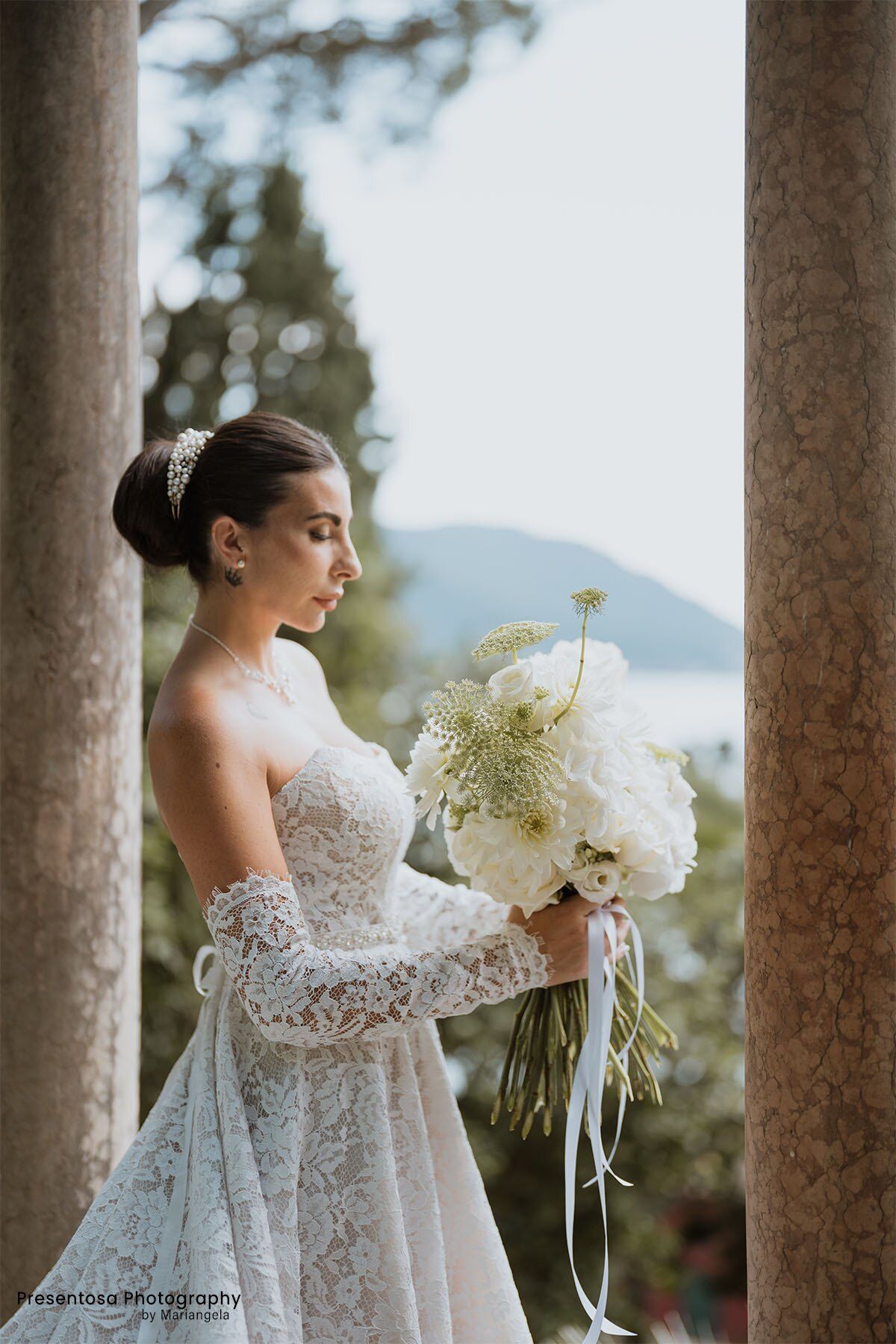 Sposa con un bouquet bianco a cascata tra le colonne